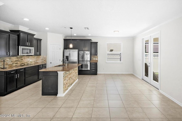 kitchen featuring appliances with stainless steel finishes, a sink, decorative backsplash, and light stone counters