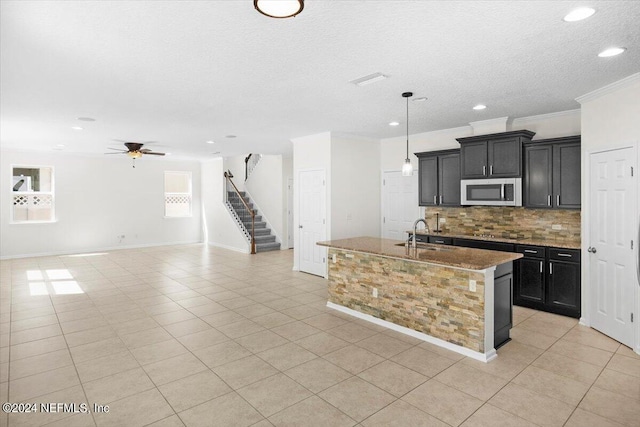 kitchen featuring crown molding, black electric stovetop, tasteful backsplash, stainless steel microwave, and a sink