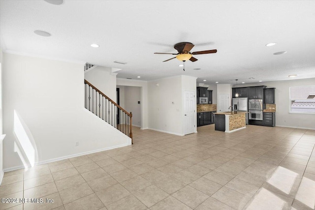 unfurnished living room featuring ceiling fan, recessed lighting, a sink, baseboards, and stairs