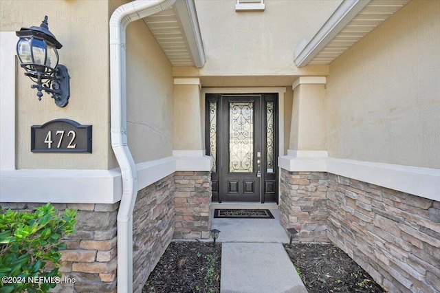 view of exterior entry with stone siding and stucco siding