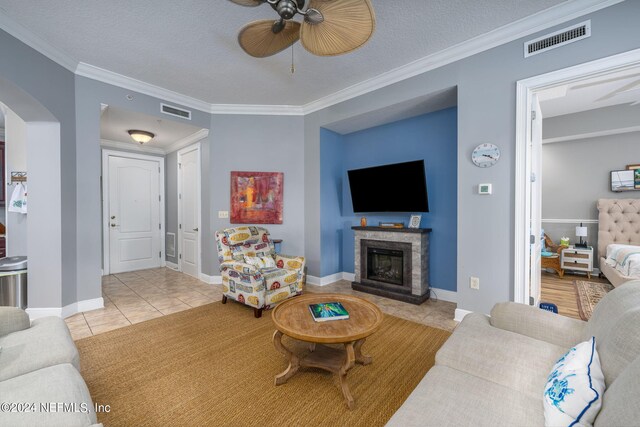 living room with ceiling fan, light tile patterned floors, a textured ceiling, and ornamental molding