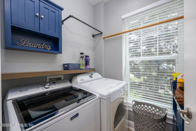 laundry area with washer and clothes dryer, cabinets, and plenty of natural light