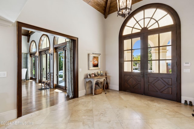 entryway with high vaulted ceiling, wooden ceiling, light wood-type flooring, french doors, and a notable chandelier