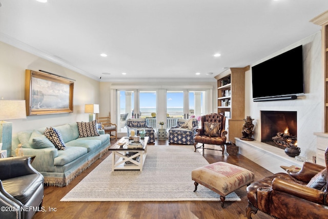 living room featuring wood-type flooring, ornamental molding, a high end fireplace, and french doors