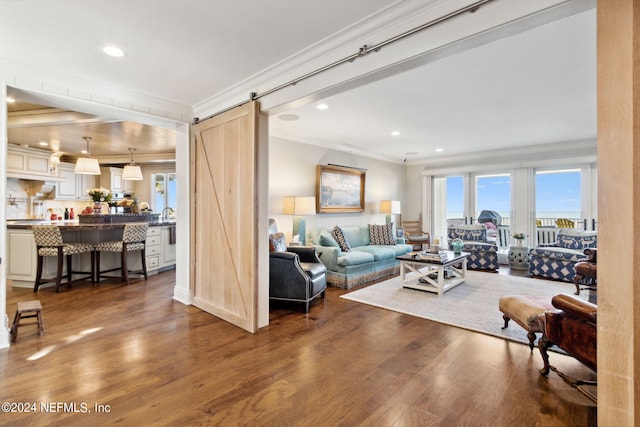 living room with a barn door, crown molding, and dark hardwood / wood-style floors