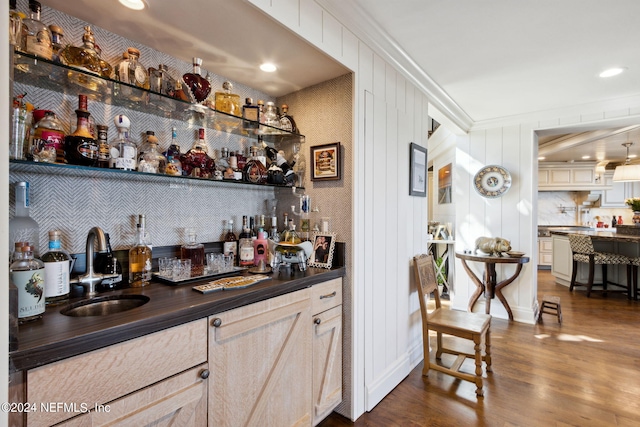 bar featuring dark hardwood / wood-style floors, sink, wood walls, light brown cabinets, and crown molding