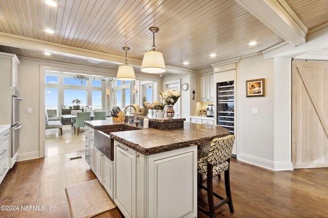 kitchen with pendant lighting, an island with sink, sink, and dark hardwood / wood-style flooring