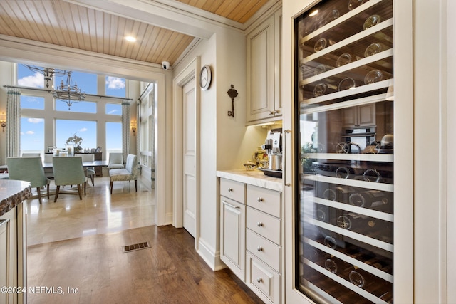 bar with cream cabinetry, wine cooler, dark hardwood / wood-style flooring, wooden ceiling, and an inviting chandelier