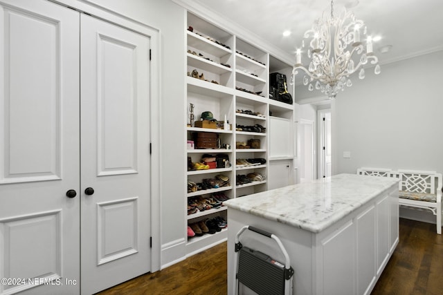 spacious closet with dark hardwood / wood-style floors and a notable chandelier