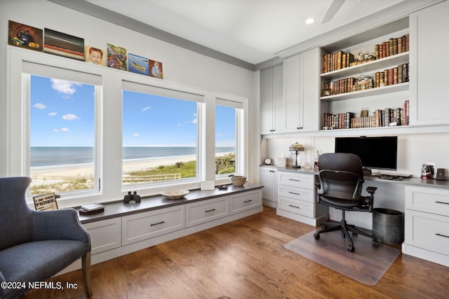 home office featuring hardwood / wood-style flooring, built in desk, and a water view