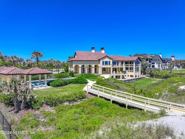 back of house with a lawn, a balcony, and a pool