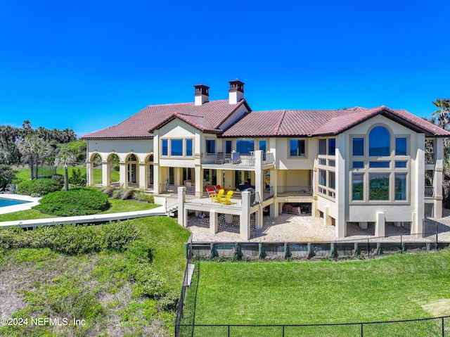 back of house featuring a balcony and a yard