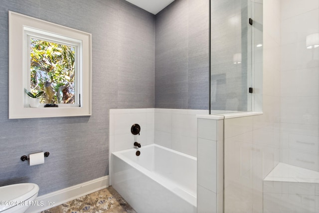 bathroom with a tub to relax in and toilet