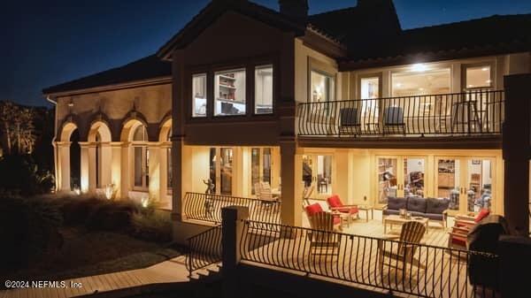 back house at night featuring a balcony and outdoor lounge area