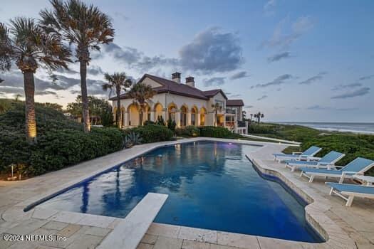 view of swimming pool featuring a water view, a patio area, and a diving board