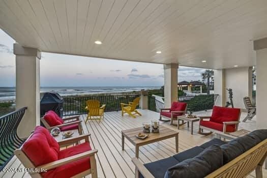 wooden deck featuring grilling area, an outdoor living space, and a water view