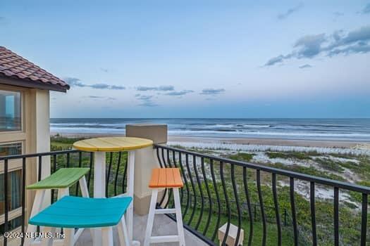 balcony featuring a water view and a beach view