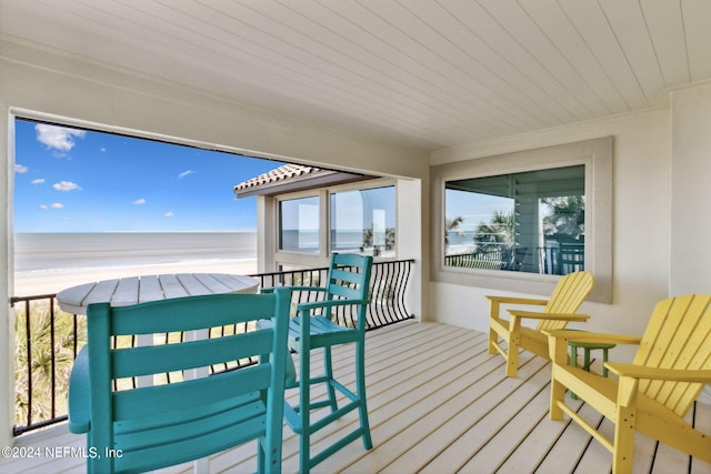 wooden deck with a water view and a beach view