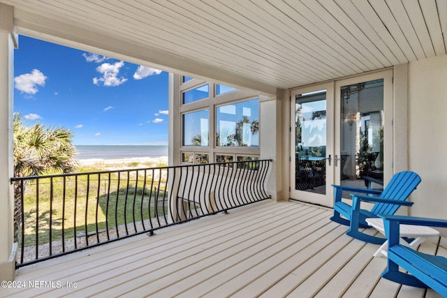 wooden deck with a water view and a view of the beach