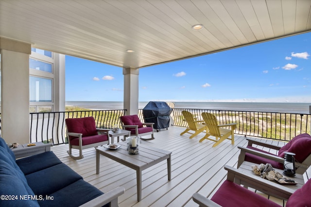 deck featuring an outdoor hangout area, grilling area, a water view, and a view of the beach