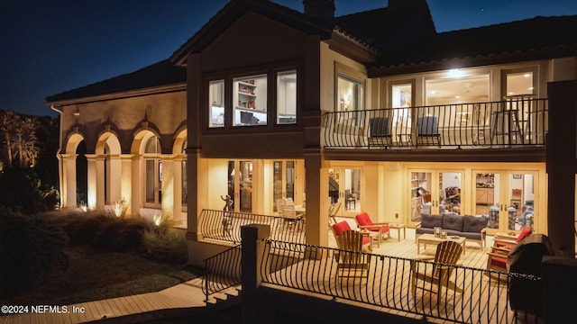 back house at twilight featuring a balcony and an outdoor living space