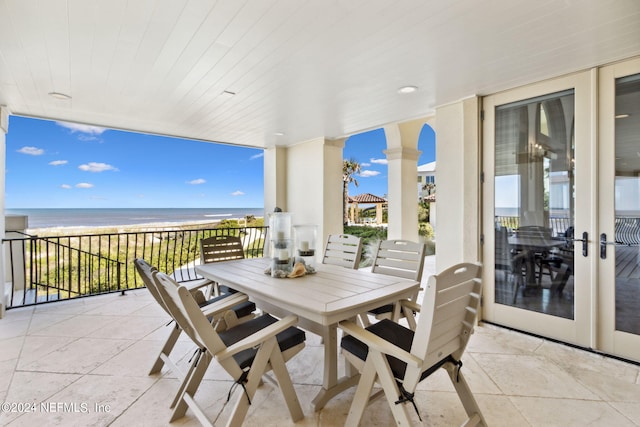 view of patio with a balcony, a water view, and a view of the beach