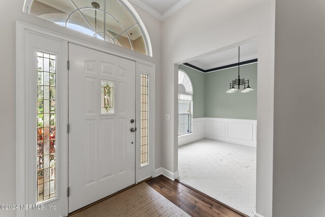 foyer with an inviting chandelier, crown molding, and dark hardwood / wood-style floors