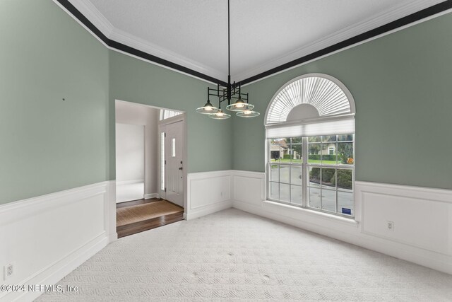 carpeted spare room featuring ornamental molding and an inviting chandelier