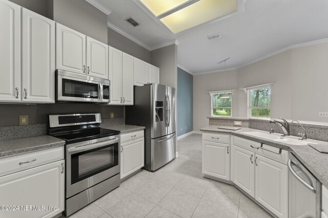 kitchen featuring light tile patterned flooring, sink, ornamental molding, white cabinetry, and appliances with stainless steel finishes