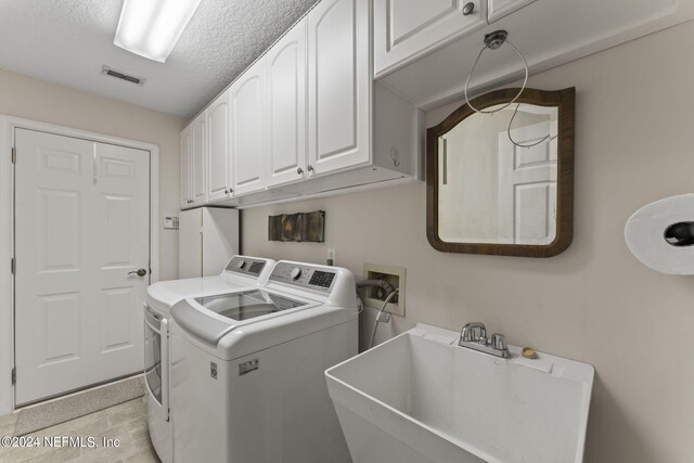 washroom featuring cabinets, a textured ceiling, washer and dryer, and sink