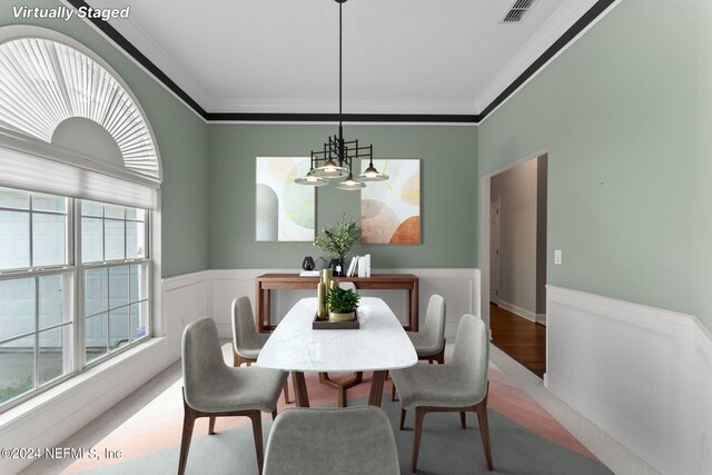 dining space featuring a healthy amount of sunlight, ornamental molding, and a chandelier