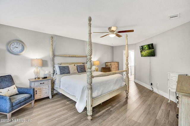 bedroom featuring a ceiling fan, visible vents, baseboards, and wood finished floors