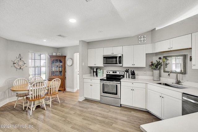 kitchen featuring visible vents, white cabinets, stainless steel appliances, light countertops, and a sink