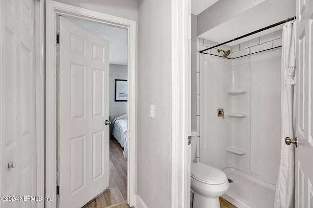 full bath featuring a textured wall, wood finished floors, toilet, and a shower with curtain