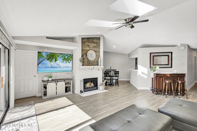 living room with lofted ceiling, a brick fireplace, baseboards, and wood finished floors