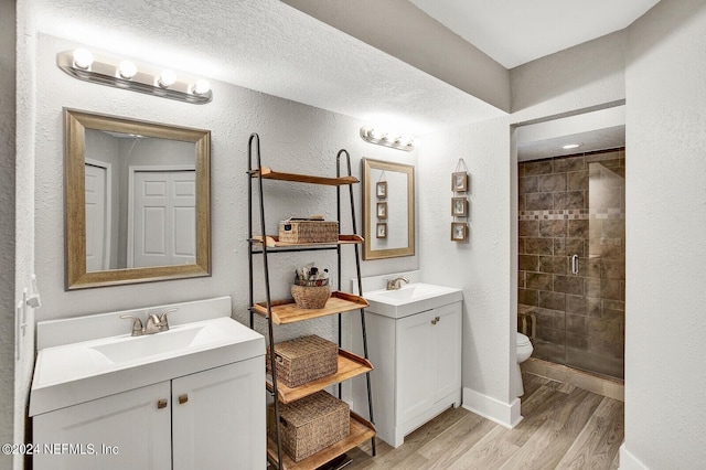 bathroom featuring a textured wall, a shower stall, a sink, and wood finished floors