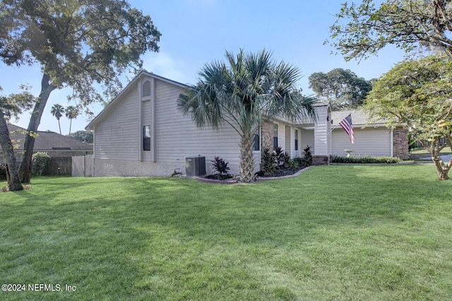 view of side of home with a lawn, cooling unit, and fence