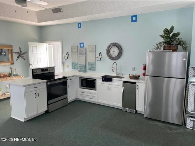 kitchen with white cabinets, a peninsula, stainless steel appliances, light countertops, and a sink