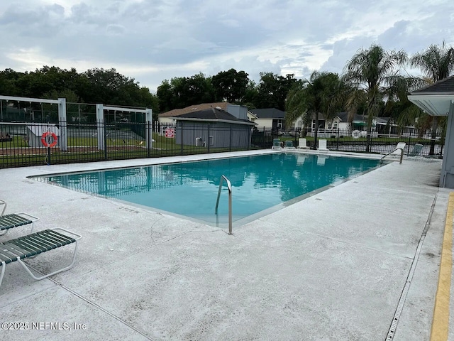 pool with a patio area and fence