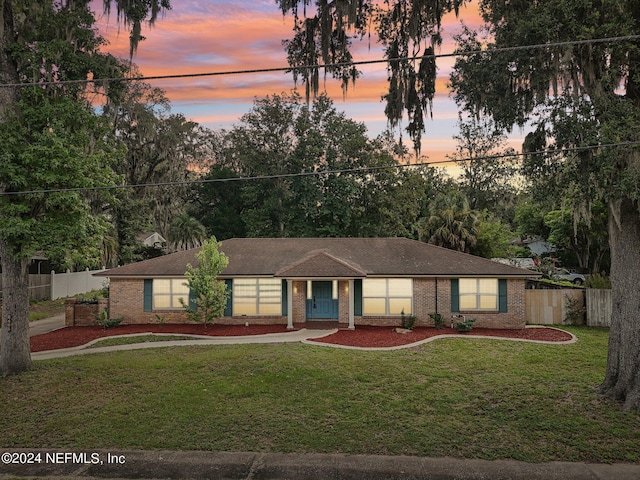 single story home featuring brick siding, fence, and a yard