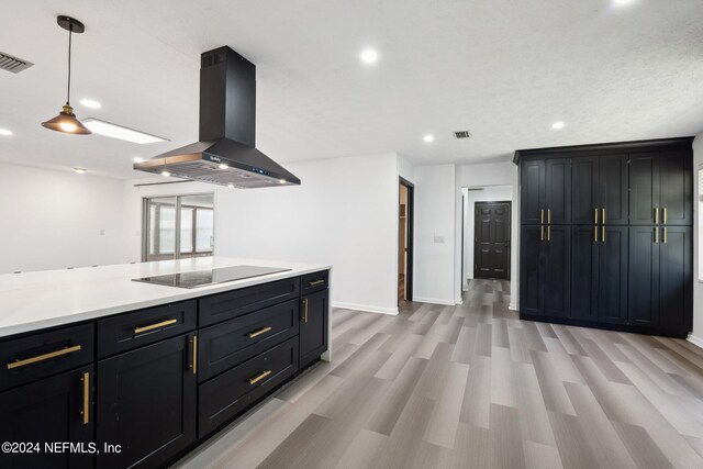 kitchen with light wood-type flooring, black electric stovetop, a textured ceiling, decorative light fixtures, and island range hood