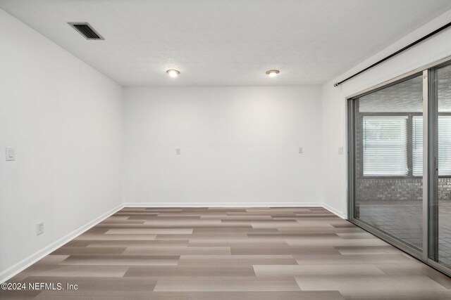 unfurnished room featuring light wood-type flooring and a textured ceiling