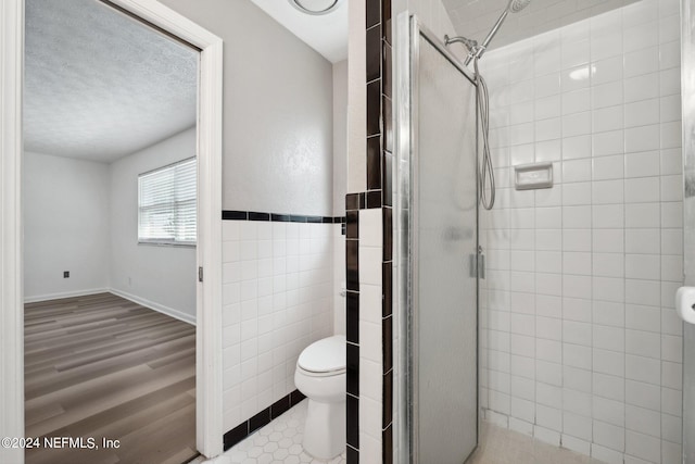 bathroom featuring an enclosed shower, wood-type flooring, toilet, and a textured ceiling