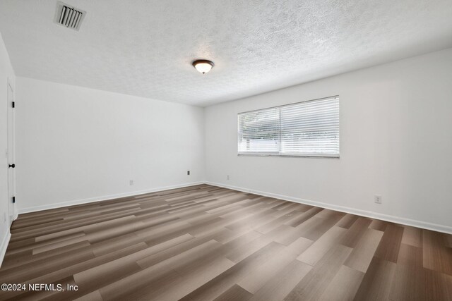 empty room with hardwood / wood-style flooring and a textured ceiling