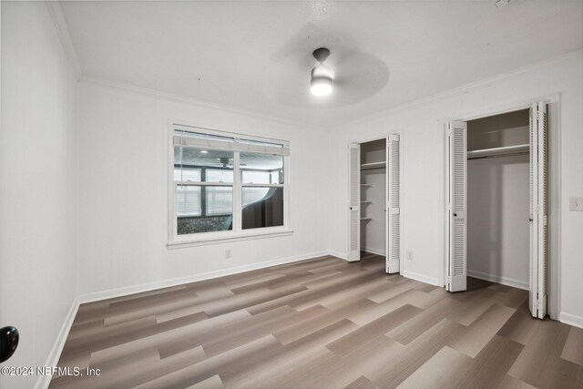 unfurnished bedroom featuring two closets, ceiling fan, ornamental molding, and light hardwood / wood-style flooring