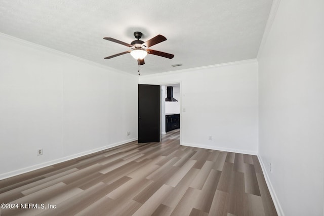 unfurnished room featuring a textured ceiling, crown molding, ceiling fan, and light wood-type flooring