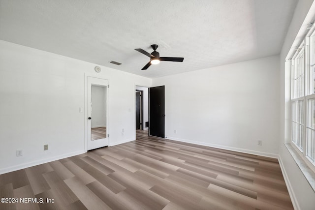 unfurnished bedroom featuring multiple windows, a textured ceiling, and wood-type flooring