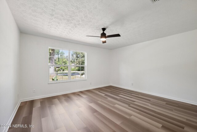 spare room with a textured ceiling, ceiling fan, and wood-type flooring