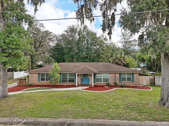 ranch-style home featuring a front yard, brick siding, and fence