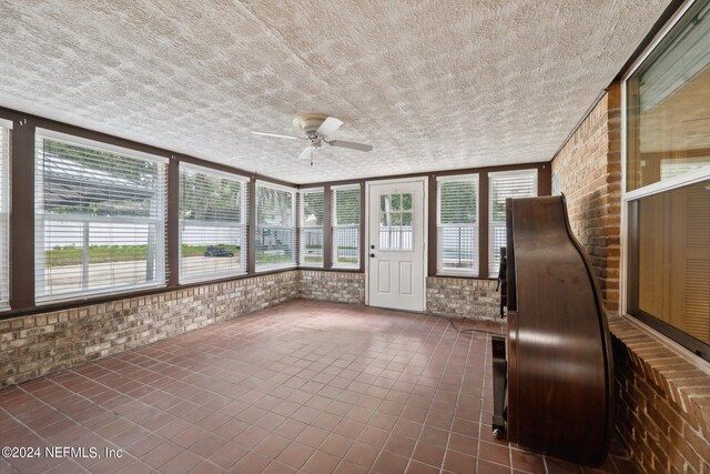 unfurnished sunroom with ceiling fan